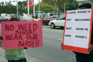 Protestors carry signs outside Uncle Ike’s Pot Shop in Seattle. Photo by Patrick Wagner. 