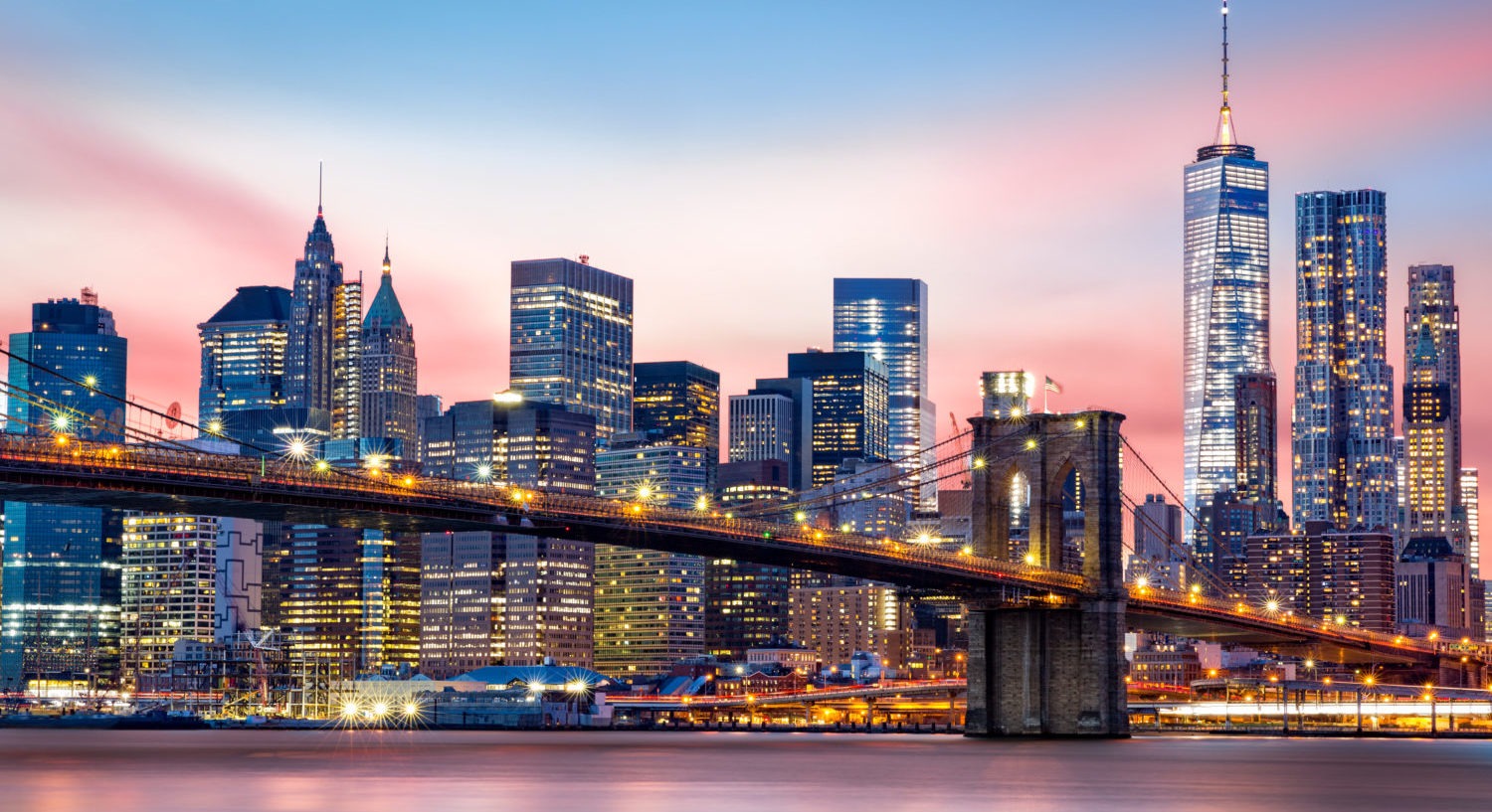 Brooklyn Bridge at and the Lower Manhattan skyline under a purple sunset